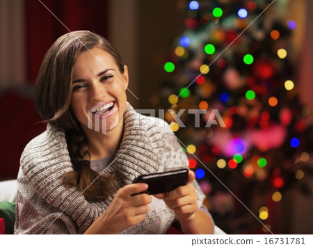 Happy young woman writing sms near christmas tree 16731781