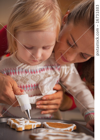 Mother and baby decorating homemade christmas cookies with glaze Mother and baby decorating homemade christmas cookies with glaze 16731883