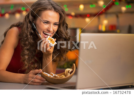 Happy young woman with christmas cookies having video chat on la 16732478
