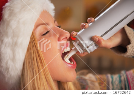 Portrait of teenage girl in santa hat eating whipped cream 16732642