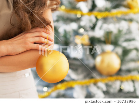 Closeup on christmas ball in hand of young woman standing near c Closeup on christmas ball in hand of young woman standing near c 16732986
