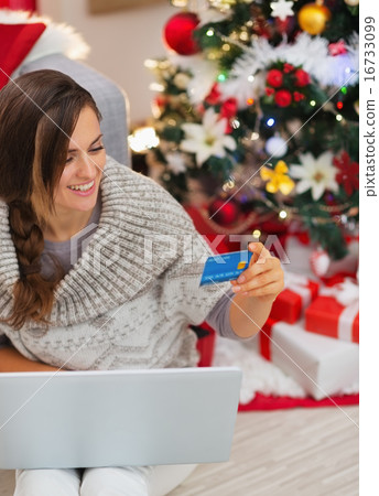 Smiling woman with laptop and credit card near Christmas tree Smiling woman with laptop and credit card near Christmas tree 16733099