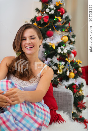 Smiling young woman in pajamas near Christmas tree 16733132
