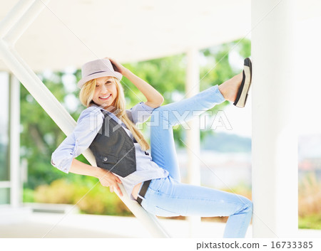 Smiling hipster girl sitting on urban structure 16733385