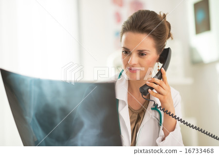 Medical doctor woman looking on fluorography and talking phone Medical doctor woman looking on fluorography and talking phone 16733468