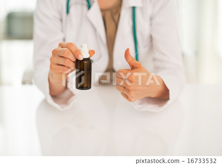 Closeup on doctor woman showing medicine bottle and thumbs up Closeup on doctor woman showing medicine bottle and thumbs up 16733532