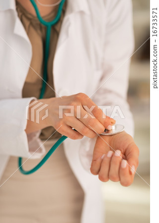 Closeup on medical doctor woman measuring pulse using stethoscop Closeup on medical doctor woman measuring pulse using stethoscop 16733571