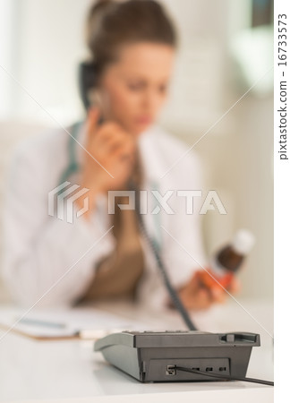 Closeup on medical doctor woman with medicine bottle talking pho Closeup on medical doctor woman with medicine bottle talking pho 16733573