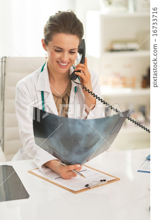 Smiling doctor woman with fluorography talking phone Smiling doctor woman with fluorography talking phone 16733716