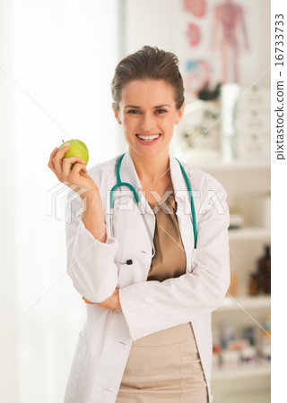 Smiling medical doctor woman with apple Smiling medical doctor woman with apple 16733733