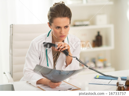 Concerned doctor woman with fluorography holding phone Concerned doctor woman with fluorography holding phone 16733737