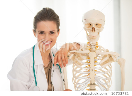 Portrait of smiling medical doctor woman near human skeleton ana 16733781
