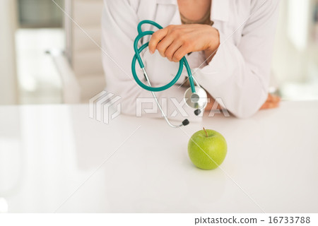 Closeup on medical doctor woman with stethoscope and apple Closeup on medical doctor woman with stethoscope and apple 16733788