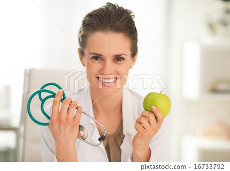 Happy medical doctor woman showing apple and stethoscope Happy medical doctor woman showing apple and stethoscope 16733792
