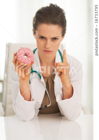 Serious doctor woman with donut threatening with finger Serious doctor woman with donut threatening with finger 16733795