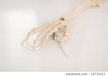 Closeup on human skeleton hand holding syringe 16733812