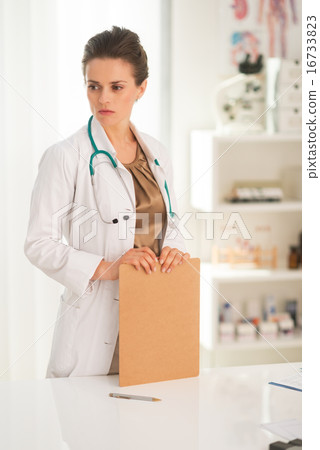 Thoughtful medical doctor woman with clipboard Thoughtful medical doctor woman with clipboard 16733823