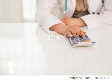 Closeup on medical doctor woman using calculator Closeup on medical doctor woman using calculator 16733827