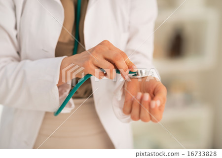 Closeup on medical doctor woman measuring pulse using stethoscop Closeup on medical doctor woman measuring pulse using stethoscop 16733828