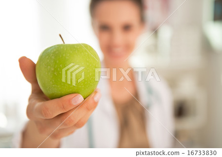 Closeup on happy medical doctor woman giving apple Closeup on happy medical doctor woman giving apple 16733830