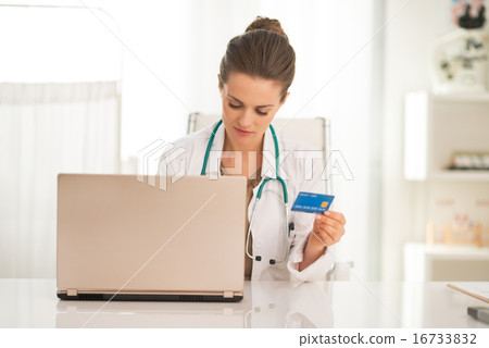Medical doctor woman with credit card using laptop Medical doctor woman with credit card using laptop 16733832
