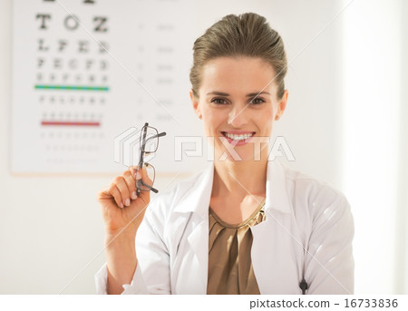 Happy ophthalmologist doctor woman with eyeglasses in front of s Happy ophthalmologist doctor woman with eyeglasses in front of s 16733836