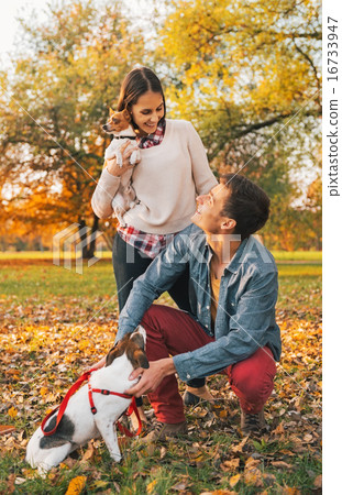 Happy young couple with dogs playing outdoors in autumn park 16733947