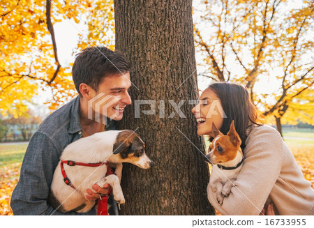 Portrait of happy young couple with dogs outdoors in autumn park Portrait of happy young couple with dogs outdoors in autumn park 16733955
