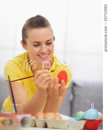 Happy young woman drawing on Easter red egg Happy young woman drawing on Easter red egg 16733960