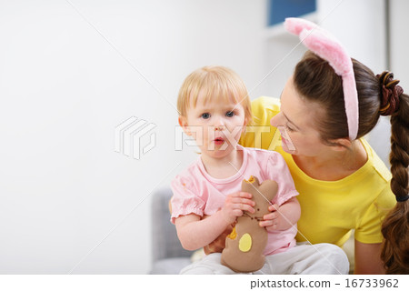 Baby sitting on mother lap and enjoying Easter rabbit cookie Baby sitting on mother lap and enjoying Easter rabbit cookie 16733962