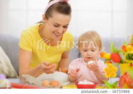 Happy mother and baby eating Easter eggs Happy mother and baby eating Easter eggs 16733966