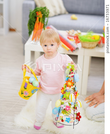 Baby holding basket of Easter eggs and decoration Baby holding basket of Easter eggs and decoration 16733971