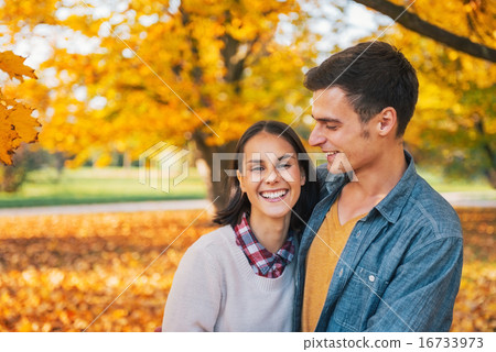 Portrait of smiling young couple outdoors in park in autumn 16733973