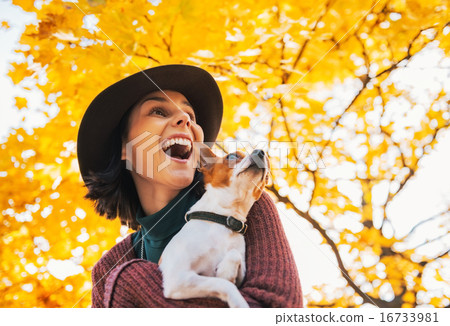 Portrait of happy young woman with dog outdoors in autumn lookin Portrait of happy young woman with dog outdoors in autumn lookin 16733981