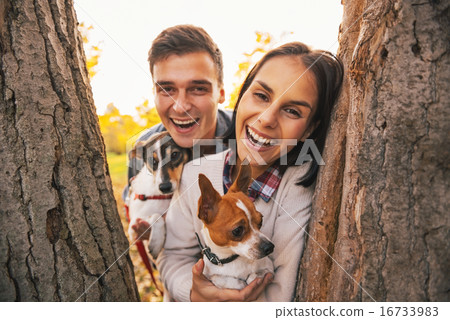 Portrait of happy young couple with dogs outdoors in autumn park Portrait of happy young couple with dogs outdoors in autumn park 16733983