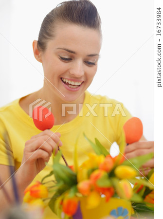 Happy young woman making Easter decoration with tulips and eggs 16733984