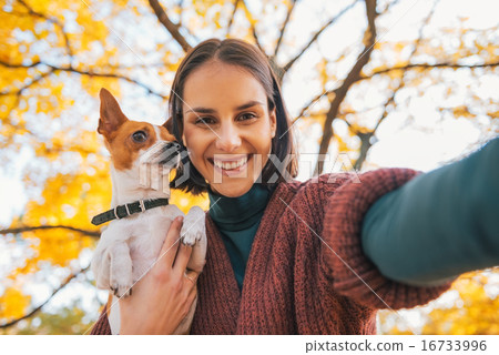 Portrait of smiling young woman with dog outdoors in autumn maki Portrait of smiling young woman with dog outdoors in autumn maki 16733996