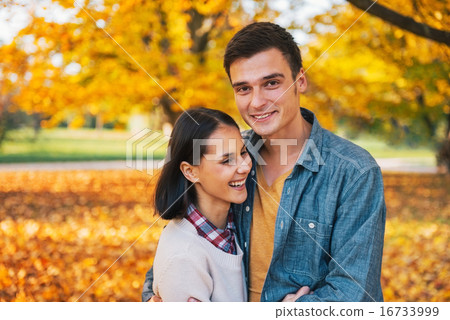 Portrait of happy young couple outdoors in park in autumn Portrait of happy young couple outdoors in park in autumn 16733999