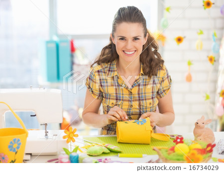 Happy young woman making easter decoration in studio 16734029