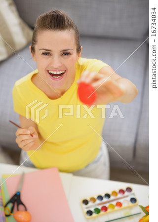 Smiling young woman showing Easter red egg 16734034