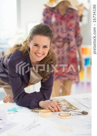 Happy fashion designer choosing accessories for garment Happy fashion designer choosing accessories for garment 16734186