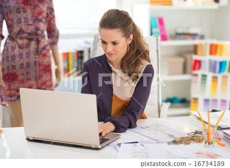 Fashion designer working on laptop in office Fashion designer working on laptop in office 16734189