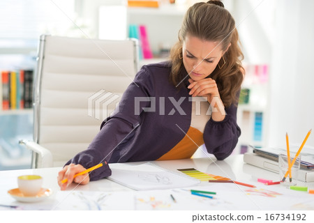 Thoughtful fashion designer working in office Thoughtful fashion designer working in office 16734192