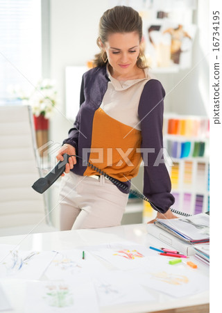 Portrait of thoughtful fashion designer with phone 16734195