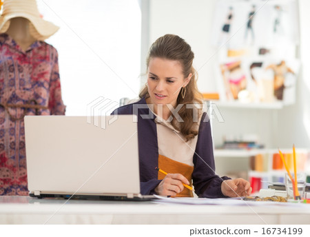 Fashion designer with laptop working in office Fashion designer with laptop working in office 16734199