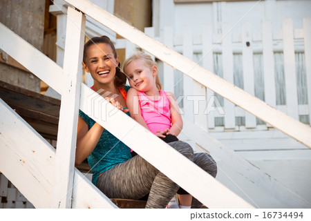 Healthy mother and baby girl sitting on stairs of beach house Healthy mother and baby girl sitting on stairs of beach house 16734494