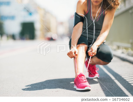 Closeup on fitness young woman tying shoelaces in the city 16734602