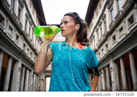 Fitness woman drinking water near uffizi gallery in florence, it 16735109