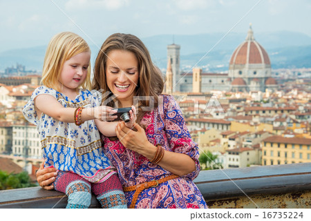 Happy mother and baby girl checking photos in camera against pan Happy mother and baby girl checking photos in camera against pan 16735224