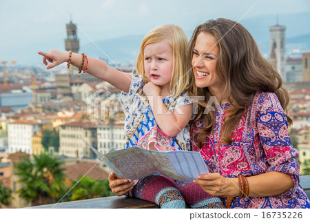 Happy mother and baby girl pointing against panoramic view of fl 16735226